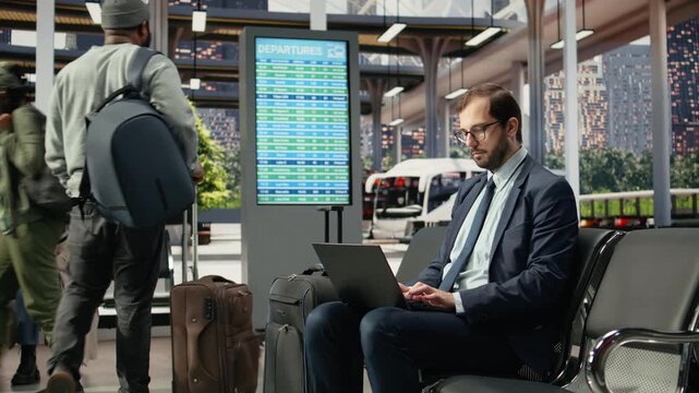 Business traveler works on a laptop in a bus station during long-distance travel, typing to complete work assignments while waiting in the coach station.