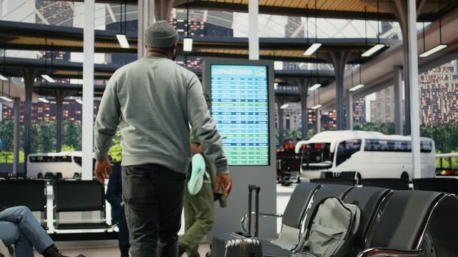 Passengers check electronic timetable in busy bus terminal