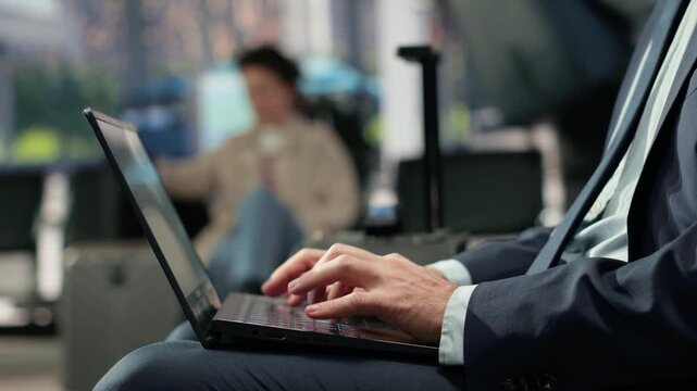 Business traveler uses a notebook in a bus terminal during a work trip, finishing online tasks before catching a bus connection during the weekday routine.