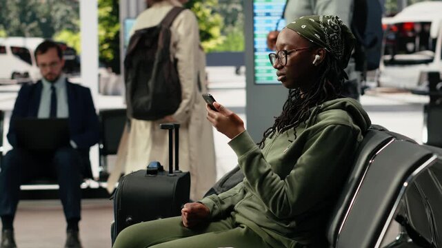 Traveler dictates a voice message on a smartphone in a bus terminal, holding the mobile phone near her mouth in the coach terminal while recording an audio message before departure.
