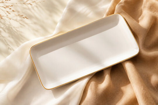 White rectangular dish with gold trim sits on flowing fabric. This elegant serving platter is perfect for snacks or small bites at parties and gatherings, adding a luxurious touch to any event.