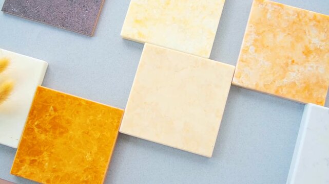 Flat lay top view tracking shot of various marble, granite, and ceramic tile material samples for interior design, architecture, and home decor.