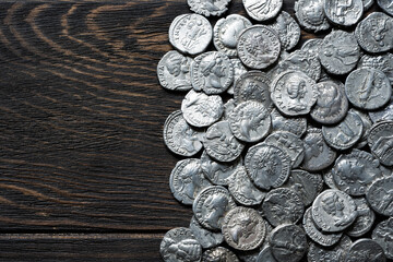 Pile of ancient Roman silver coins on a old wooden table. Historical currency and vintage money flat lay. Top view of antique money, background. © scaliger