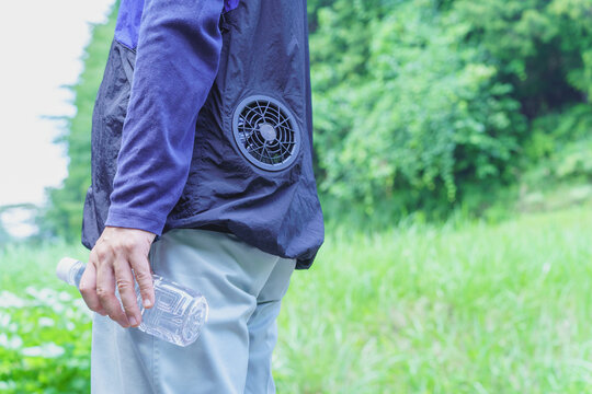 熱中症対策｜ファン付きウェアを着でペットボトルの水を持つ男性