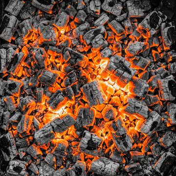 Glowing embers of burning charcoal inside a grill, preparing for summer barbecue cooking, intense heat and fire texture background
