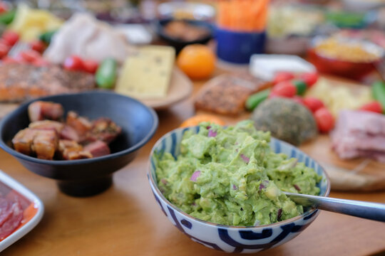 guacamole, avocado, dip, food, appetizer, brunch, buffet table spread with fresh healthy ingredients like meat cheese and vegetables on a wooden surface for a party social catering