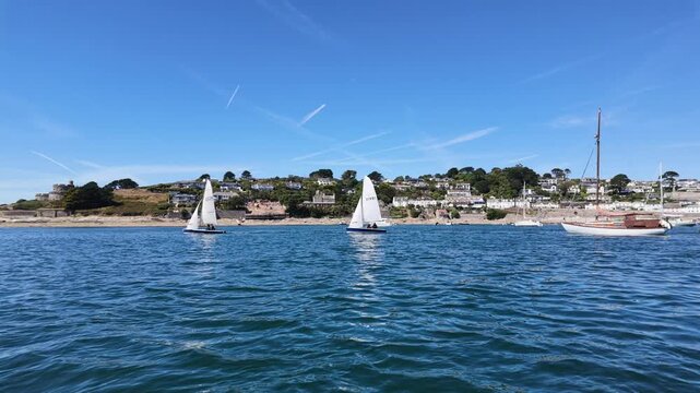 St Mawes Cornwall England UK. 13.08.2026. Video. Multiple sailboats navigate the calm, blue ocean waters with a baackground of St Mawes  