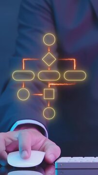 Businessman using computer mouse and keyboard vertical shot displaying glowing flowchart diagram. Algorithm execution logic, structured decision tree, and workflow programming process concept.