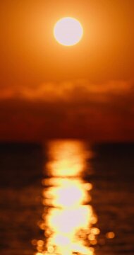 Golden Sun Setting Over Ocean With Blurred Reflection and Warm Orange Horizon Glow