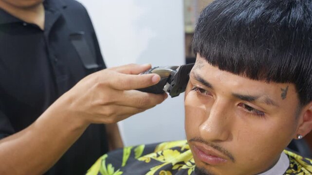 Professional barber using electric clipper on customer haircut