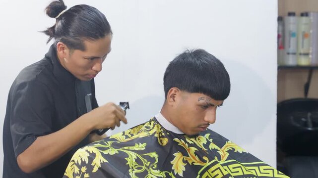 Professional barber giving man a haircut with electric clipper