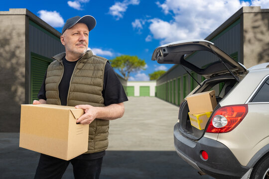 Parcel delivery logistics. Courier picks up packaged order from car trunk for shipping to storage facility and customer distribution.