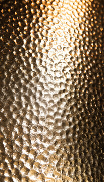 Close up of textured golden metal surface with light reflections