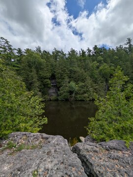 A park with beautiful conifers&mdash;cypresses and a lake whose waters flow past a rocky islands. A quiet, sunny day, with no people around. Rockwood&mdash;nature in the province of Ontario, Canada.
