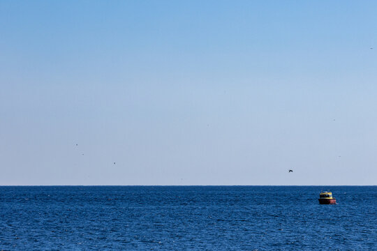 Quebec, Canada, 15 July 2026 : A red and yellow navigational buoy floats on the vast blue ocean under a clear sky.