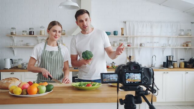 Young couple cooking food and recording video in a home kitchen