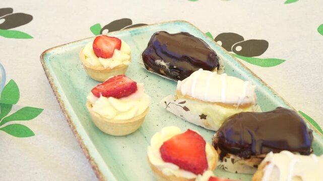 Assorted sweet mini pastries with fruit tarts and eclairs on a plate