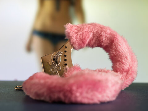 Fluffy Pink Handcuffs on Table with Model in Background