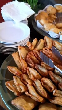 Vertical tilt down shot of Indonesian catering snack buffet featuring cream puffs and fried savory pastries