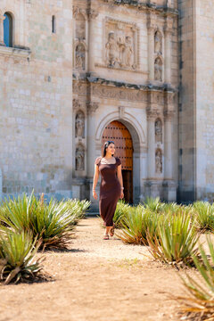 Woman in a summer dress walking through the agave garden at santo domingo de guzman church in oaxaca city, enjoying sunny historic architecture, culture and travel vibes