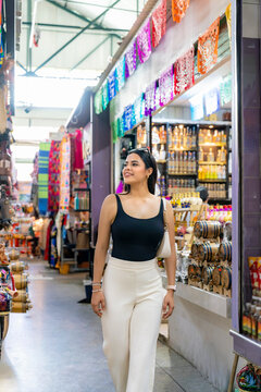 Latina woman exploring a vibrant oaxacan market, looking at colorful stalls with local products and traditional decorations, experiencing authentic mexican culture