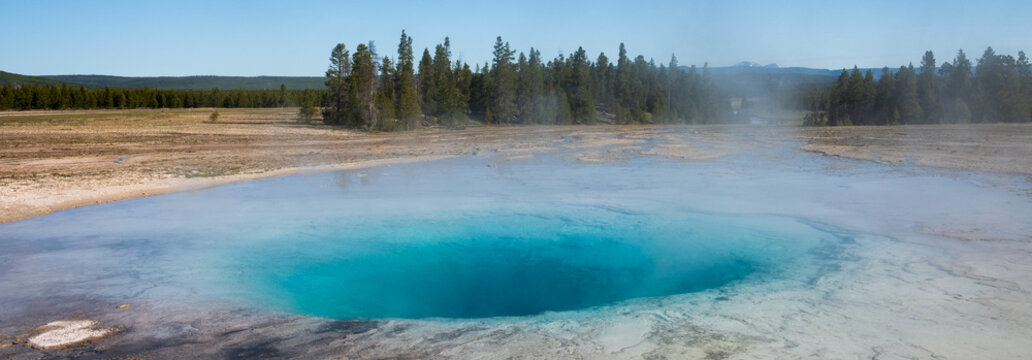 Turquoise natural geothermal pool in the midway geyser basin with hot steam on a cool morning, summer tourism at Yellowstone National Park viewing natural geothermal 
