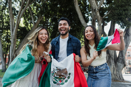 young Mexican people with flags to celebrate mexican independence day and cheering Viva Mexico