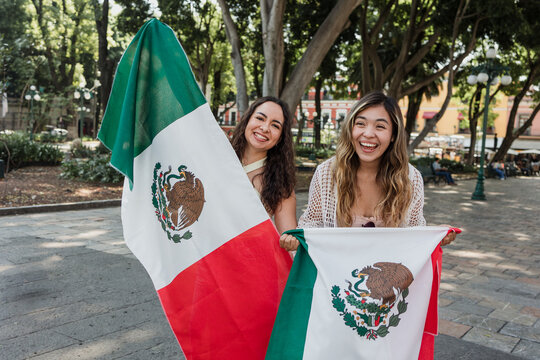 young Mexican women friends with flags to celebrate mexican independence day and cheering Viva Mexico 