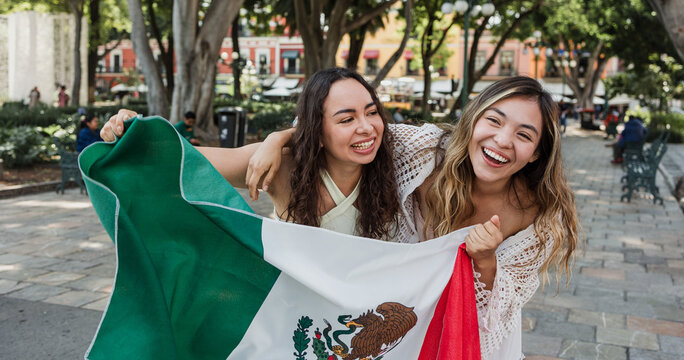 young Mexican women friends with flags to celebrate mexican independence day and cheering Viva Mexico 