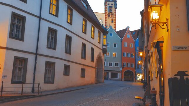 Historic old town street in F&uuml;ssen, Bavaria, Germany, with colorful traditional buildings, illuminated lanterns and medieval architecture at dusk.