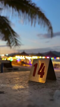 Vertical beach cafe table number fourteen close up. And glowing background at night
