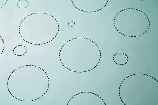 A minimal graphic pattern of various dashed circles arranged on a pale light background surface.