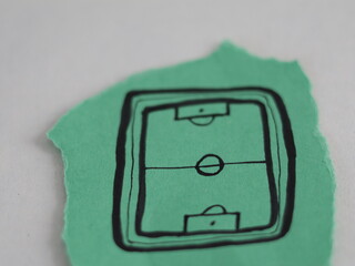 Un papel rasgado de color verde con la figura de una cancha de fútbol en un fondo blanco © Elika R