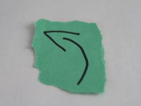 Una flecha de color verde en un papel rasgado en un fondo blanco 