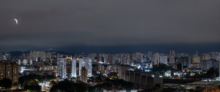 Nighttime photo of the Lapa neighborhood in Sao Paulo featuring the waning moon and the Cantareira mountain range.