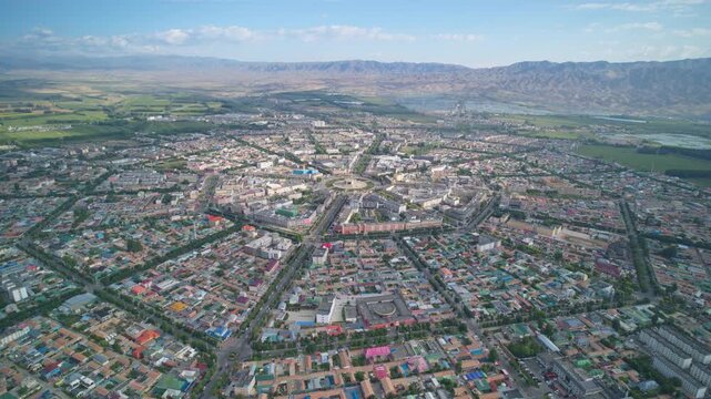 High-Angle Aerial Panoramic View of Tekes Bagua City in Ili: Unique Bagua I-Ching Geometric Layout, Radial Streets, Circular Ring Roads, Blue Sky and Mountain Range in Xinjiang