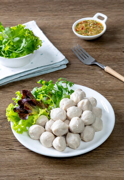 Thai pork meatballs with a spicy dipping sauce, served on a white plate.