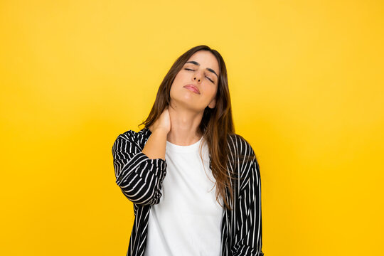 Woman experiencing discomfort and stiffness in her neck and shoulders, touching her upper trapezius muscle with eyes closed, indicating a headache, tension, or fatigue