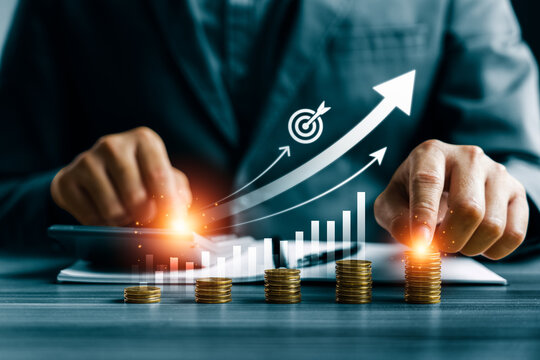 Financial growth concept with business professional using calculator and touching stacked coins showing rising arrow chart, investment profit increase and revenue success strategy