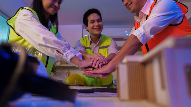 Asian construction team stacking hands together for teamwork and unity