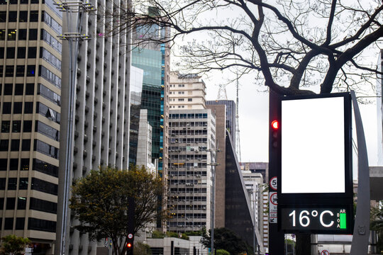 Digital billboard with blank white mockup display on Paulista Avenue. A modern street clock with an isolated white screen frame for advertisement placement,
