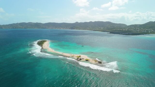 Aerial orbit moves left as narrow sandbar lined with palm trees stretches into turquoise waters off Carriacou