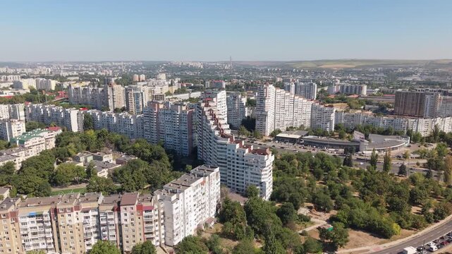 Forward aerial drone flight toward the City Gates area of Chisinau, Moldova, revealing large residential apartment blocks, Soviet-era urban architecture, greenery and the expansive capital city skylin