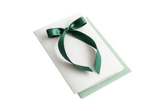 Dark green satin ribbon tied in a simple bow on a stack of white and pale green paper stationery cards isolated on a transparent background