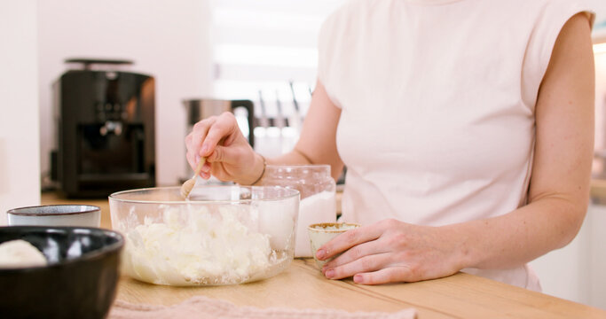 Dessert making. Culinary process. Woman confectioner hand pouring salt spoon in bowl measuring ingredient for tasty homemade dish.