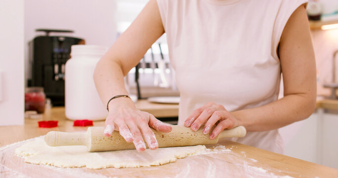 Baking home. Rolling dough pin. Female chef hand flattening sweet mass sheet on wooden kitchen table covered with flour making pastry.