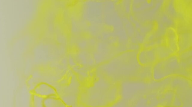 Vertical video. Splash ink. Liquid texture. Defocused yellow color acrylic water flowing fog particles floating on abstract art creative background.