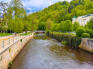 Fototapeta premium Karlovy Vary river flows through green trees and buildings in Czechia