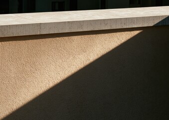 Fototapeta premium Sunlit textured wall with a sharp shadow and stone trim