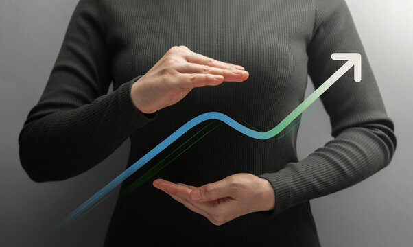 Businesswoman shields a rising graph between her hands